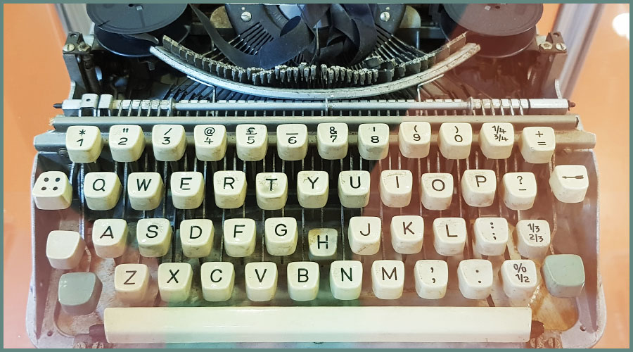 Close-up of a typewriter, quite old and battered, behind perspex