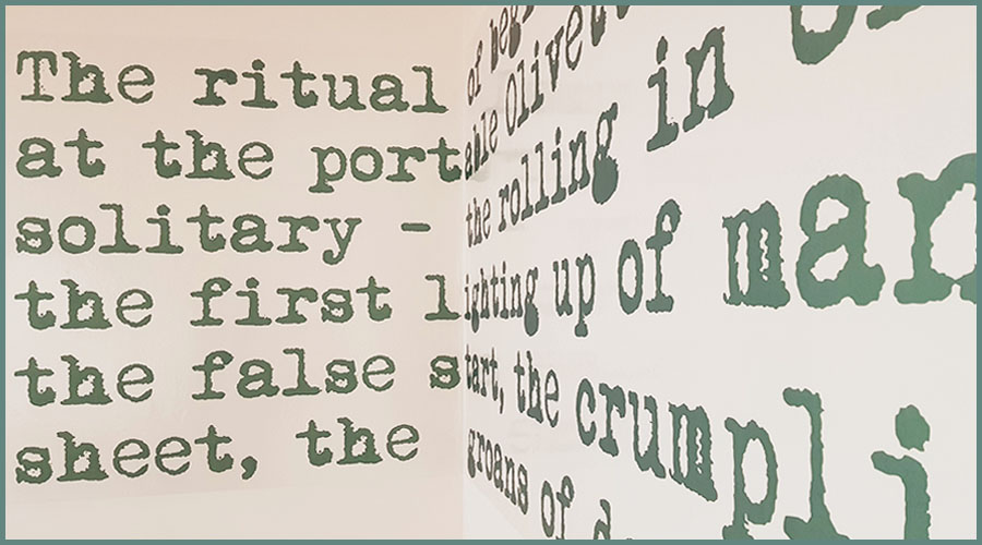 Large green text on a wall, part of a larger quote by Anthony Burgess