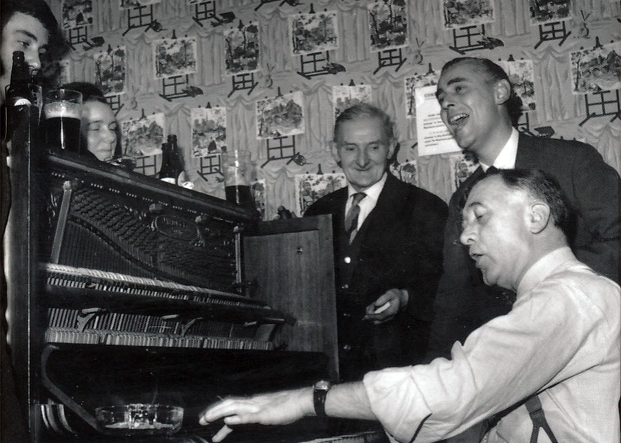 Men around a piano, playing and singing